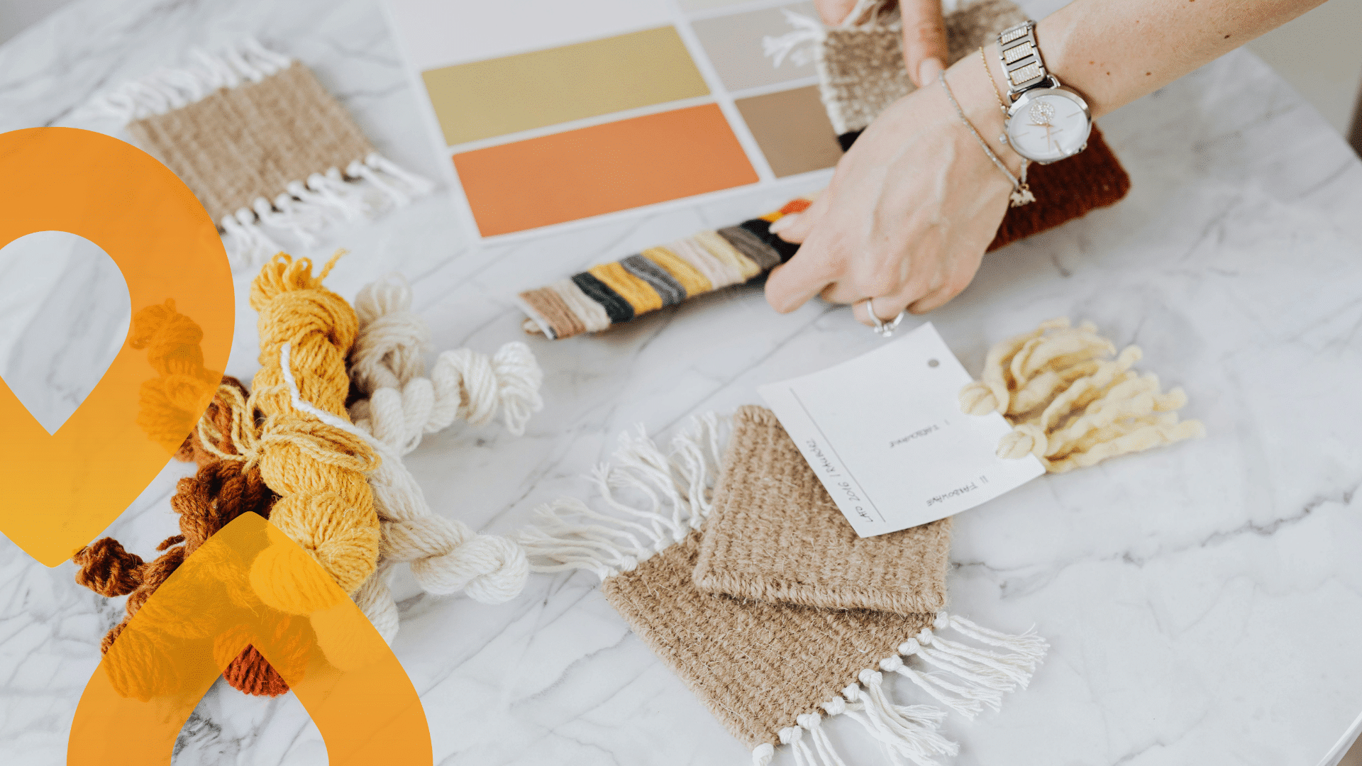 Joku tekee käsitöitä, pöydällä lankoja ja paperia