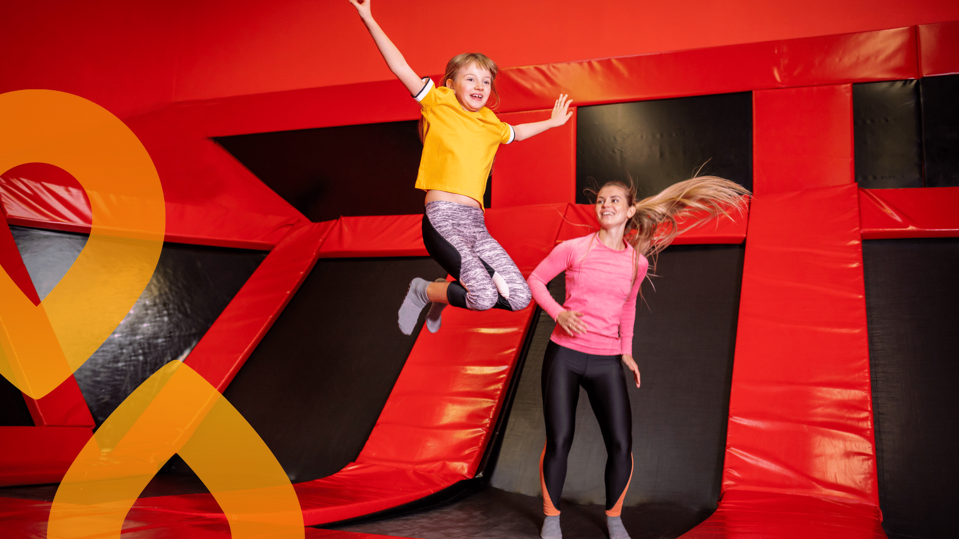 Lapsi ja aikuinen pomppimassa trampoliinipuistossa