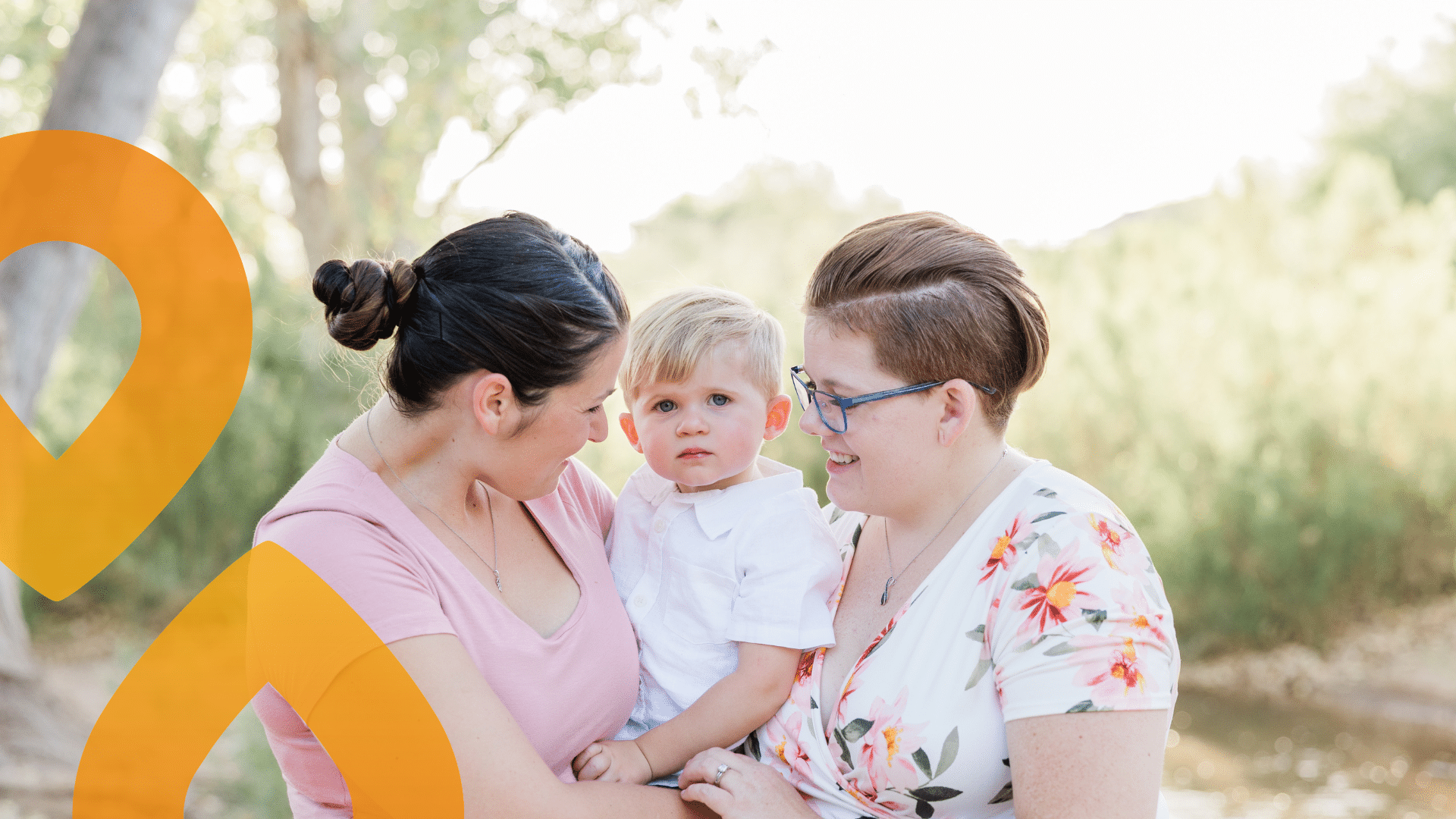 kaksi aikuista ulkona sylissään vauva
